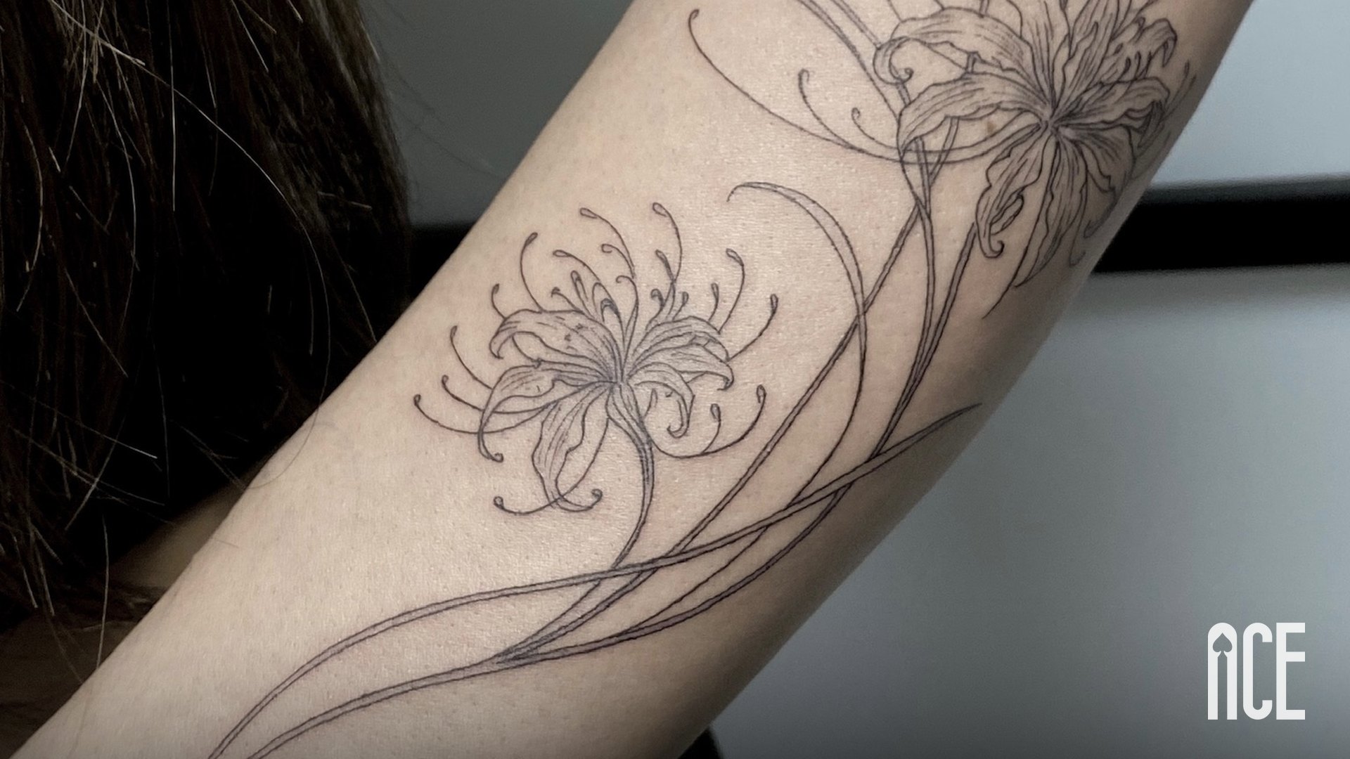 Tatuaj fine line cu crini pe braț, realizat la Ace Tattoo în Sector 1, București