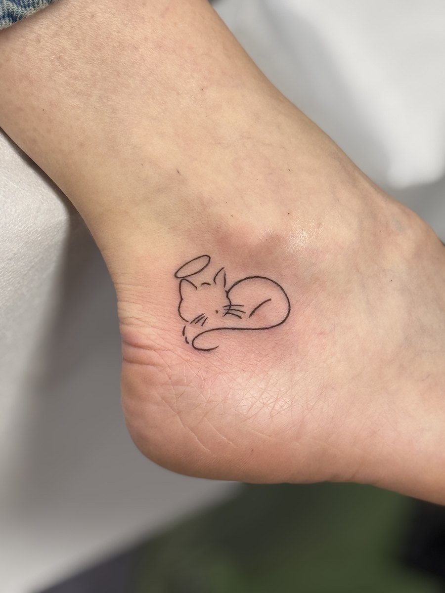 Pisică desenată dintr-o singură linie, tatuaj fine line pe gleznă, văzut dinspre călcâi, lucrare Ace Tattoo București