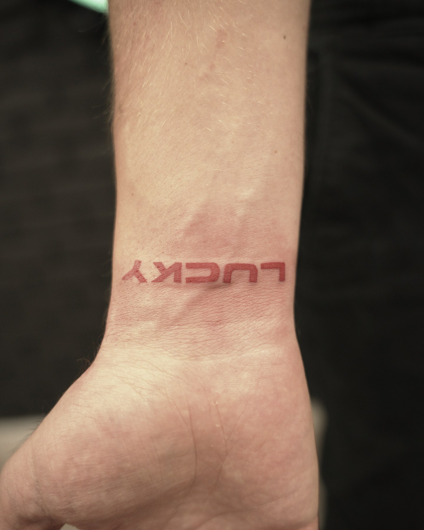 Lettering roșu «LUCKY», tatuaj color la Ace Tattoo București