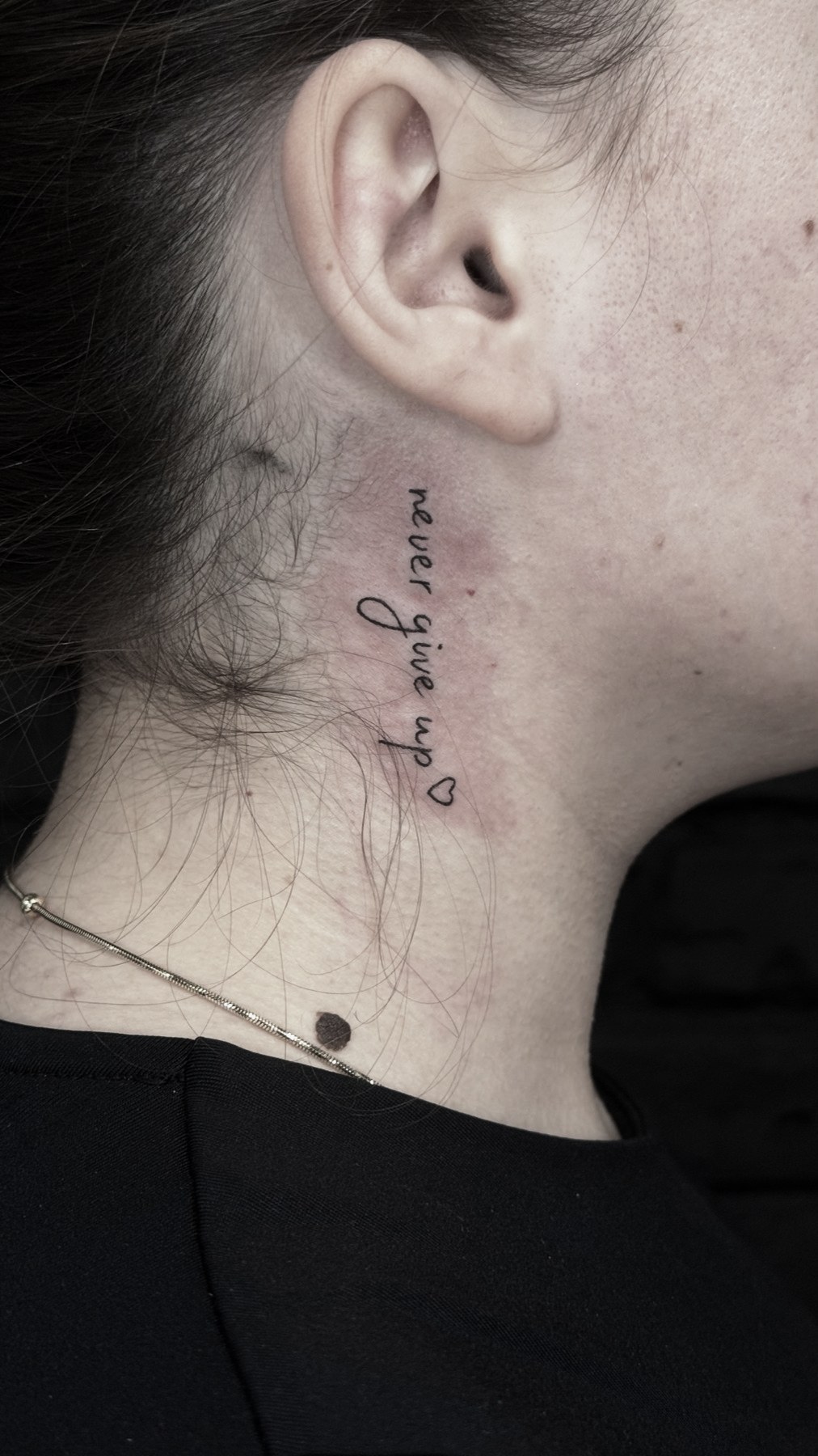 Lettering «never give up» cu inimă, tatuaj fine line de Vlad Shulea la Ace Tattoo București