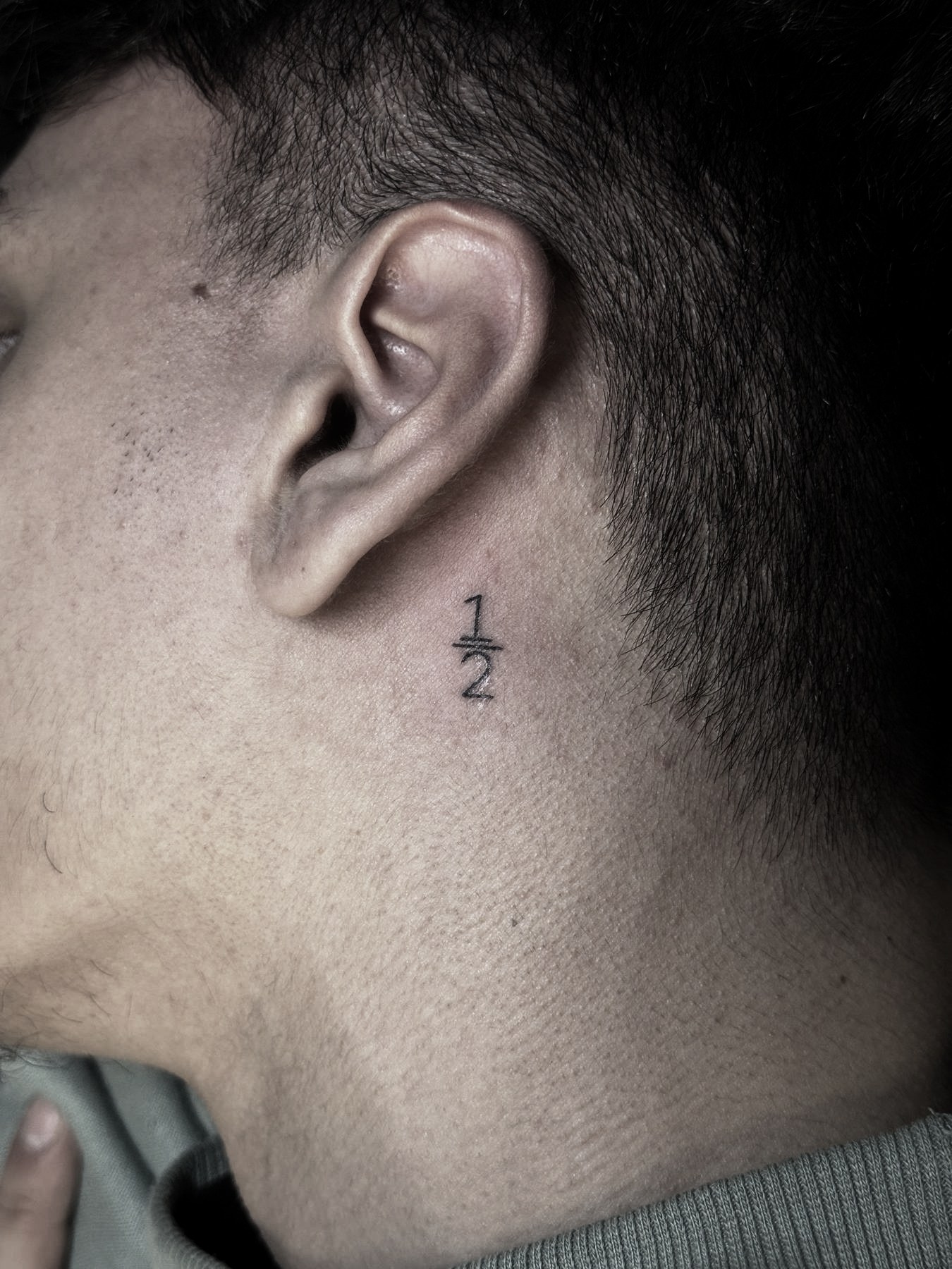 Simbol «1/2» în spatele urechii, tatuaj fine line de Vlad Shulea la Ace Tattoo București